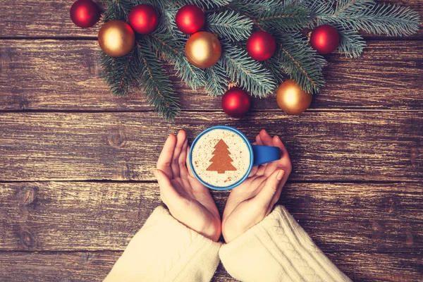 Női gazdaság csésze kávét egy tabl a krém karácsonyfa — Stock Fotó