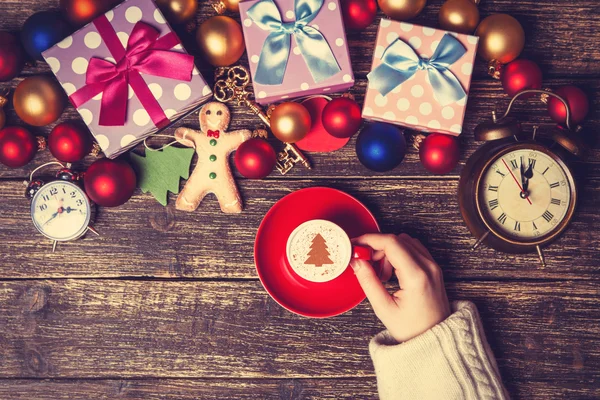 Mujer sosteniendo taza de café con árbol de Navidad crema en una tabla — Foto de Stock