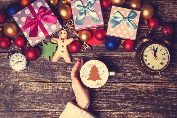 Female holding cup of coffee with cream christmas tree on a tabl — Stock Photo, Image