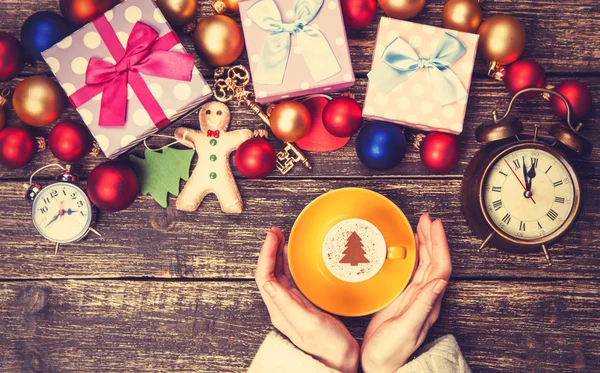 Feminino segurando xícara de café com árvore de Natal creme em uma mesa — Fotografia de Stock