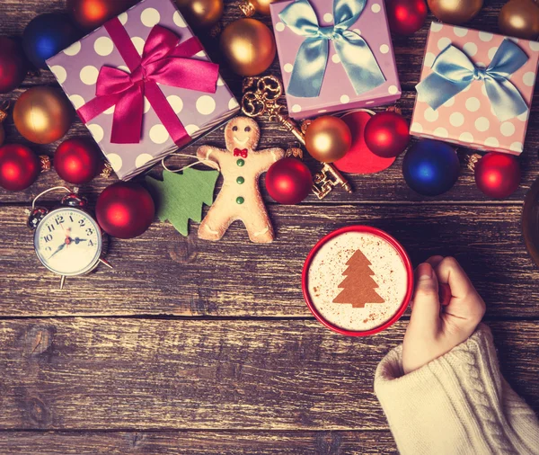 Feminino segurando xícara de café com árvore de Natal creme em uma mesa — Fotografia de Stock