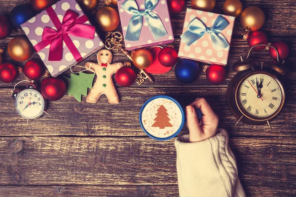 Feminino segurando xícara de café com árvore de Natal creme em uma mesa — Fotografia de Stock