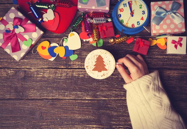 Femme tenant tasse de café avec arbre de Noël crème sur une table — Photo