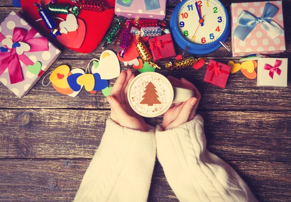 Femme tenant tasse de café avec arbre de Noël crème sur une table — Photo