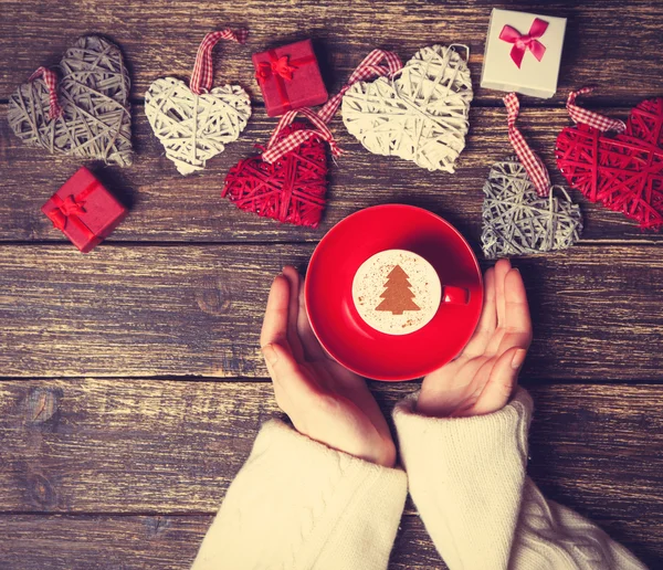 Ženské hospodářství šálek kávy s krémem vánoční strom na tabl — Stock fotografie