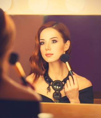 Güzel kızıl saçlı kadınlar appling makyaj aynası yakınındaki