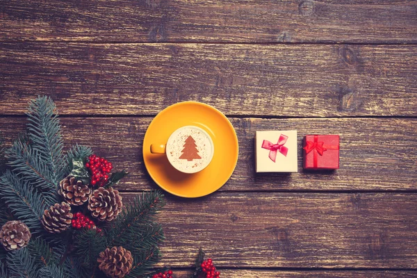 Tazza di caffè con albero di Natale alla panna e regalo su un tavolo . — Foto Stock