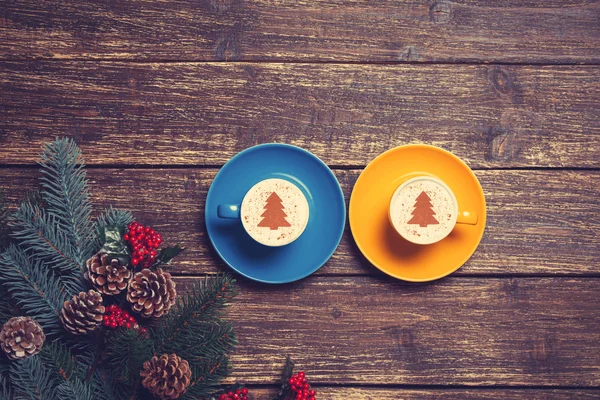 木製のテーブル上の枝の近くのクリスマス ツリーの形をした 2 つのカップ — ストック写真