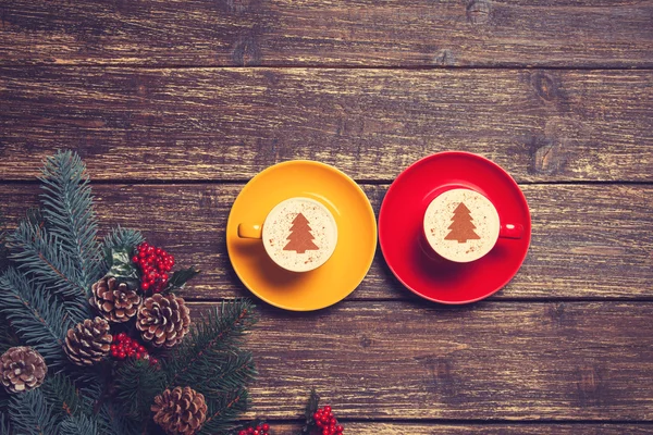 Duas xícaras com forma de árvore de natal perto do galho em uma mesa de madeira — Fotografia de Stock