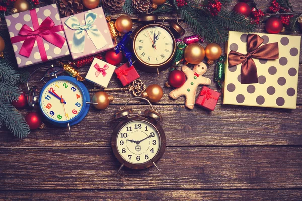 Christmas gifts, gingerbread, alarm clocks and pine branches on — Stock Photo, Image