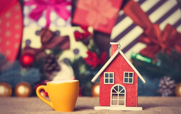 Cup of coffee and christmas house toy on a table — Stock Photo, Image