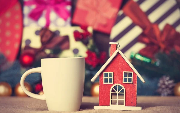 Cup of coffee and christmas house toy on a table — Stock Photo, Image