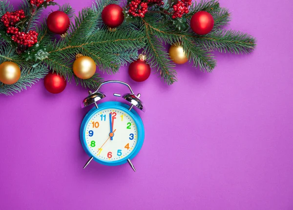 Alarm clock with pine branch on violet background. — Stock Photo, Image