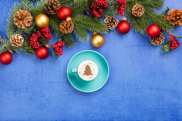 Cappuccino and christmas tree shape and pine branch on blue back — Stock Photo, Image