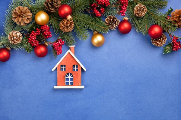 Toy house and pine branches with toys on blue background. — Stock Photo, Image