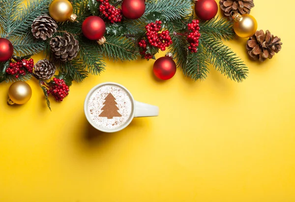 Cappuccino and christmas tree shape and pine branch on yellow ba — Stock Photo, Image