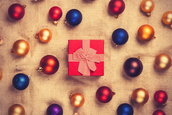 Scatola regalo e palline di colore su sfondo di iuta . — Foto Stock