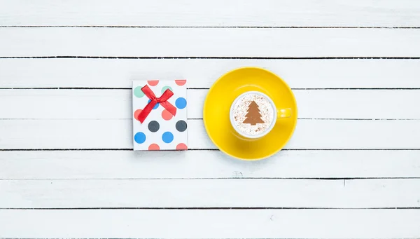 Gift box and cappuccino on white wooden table. — Stock Photo, Image