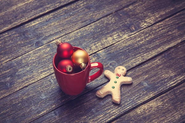 Šálek kávy a vánoční koule a perník muž na dřevěný stůl. — Stock fotografie