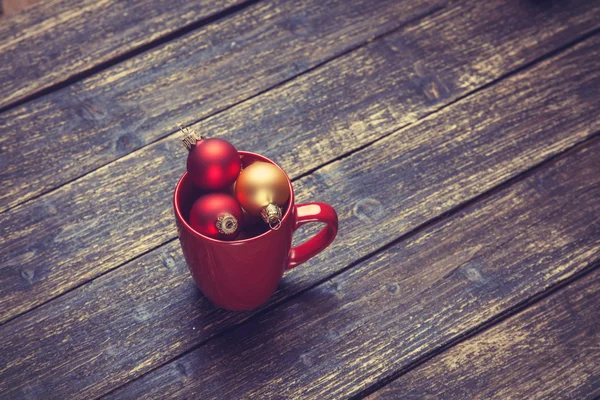Tasse mit Weihnachtskugeln auf Holztisch. — Stockfoto