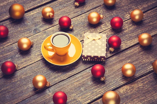 Copa de café y bolas de Navidad y regalo en la mesa de madera . — Foto de Stock