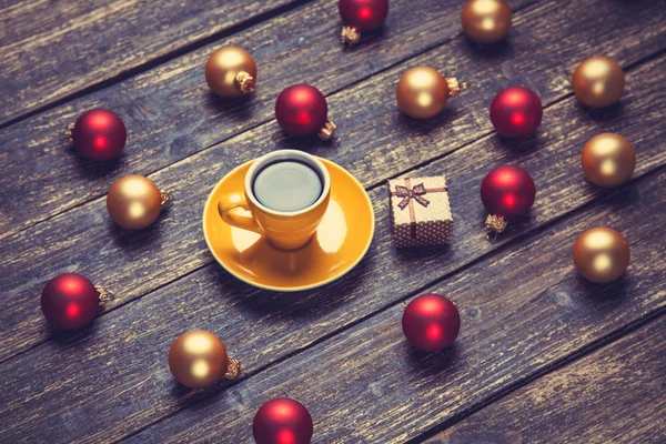 Cup of coffee and christmas balls and gift on wooden table. — Stock Photo, Image