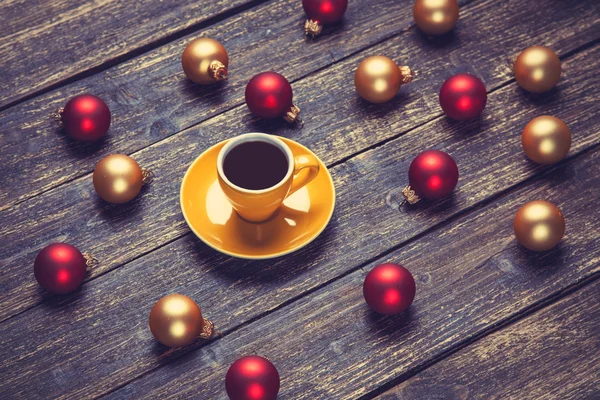Kopp kaffe och christmas bollar på träbord. — Stockfoto