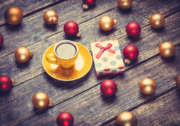 Cup of coffee and christmas balls and gift on wooden table. — Stock Photo, Image