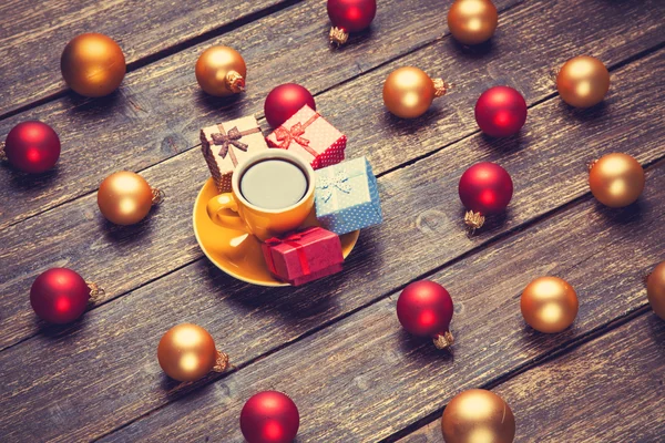 Cup of coffee and christmas balls and gift on wooden table. — Stock Photo, Image