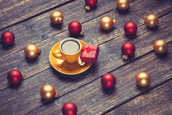 Cup of coffee and christmas balls and gift on wooden table. — Stock Photo, Image