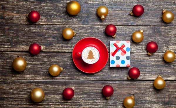 Kopp kaffe och christmas bollar och present på träbord. — Stockfoto