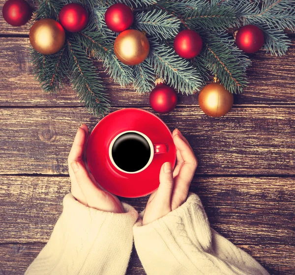 Female holding cup of coffee near pine brach on a table. — Stock Photo, Image