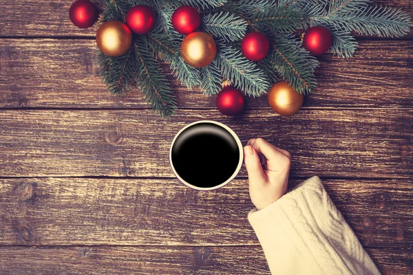 Femmina che tiene la tazza di caffè vicino a brach di pino su un tavolo . — Foto Stock