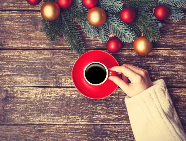 Female holding cup of coffee near pine brach on a table. — Stock Photo, Image