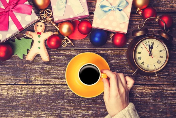 Female holding cup of coffee near christmas gifts on a table — Stock Photo, Image