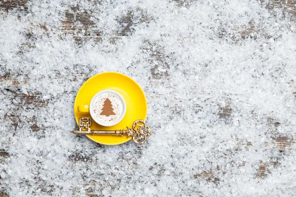 Cappuccino com forma de árvore de natal e chave na neve artificial — Fotografia de Stock