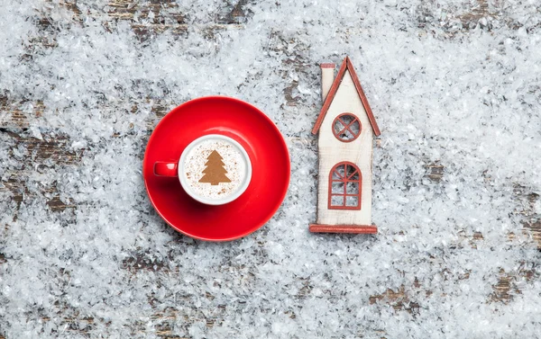 Cappuccino mit Christbaumform und Spielzeughaus auf Kunststoff — Stockfoto