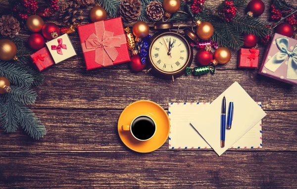 Hot coffee with letter near christmas gifts on wooden table. — Stock Photo, Image