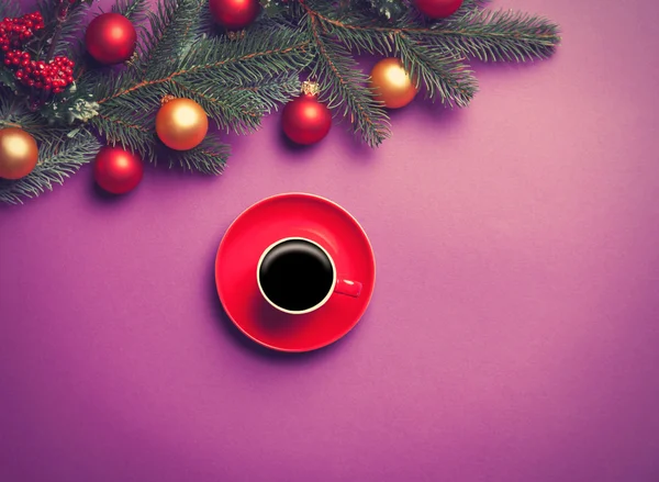 Hot coffee and pine branch with christmas toys on violet backgro — Stock Photo, Image