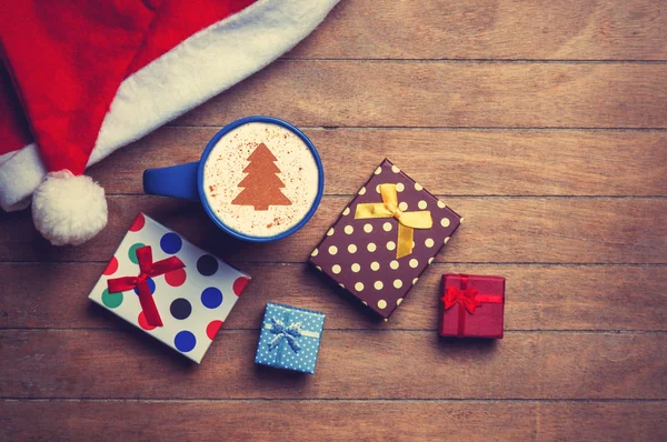 Cappuccino con sombrero de Navidad y regalo en mesa de madera . —  Fotos de Stock
