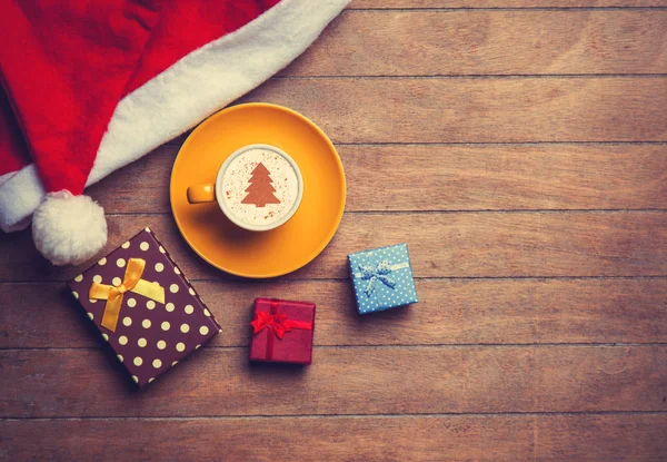 Cappuccino con cappello di Natale e regalo sulla tavola di legno . — Foto Stock