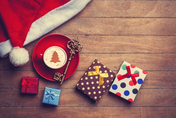 Cappuccino with christmas hat and gift on wooden table. — Stock Photo, Image