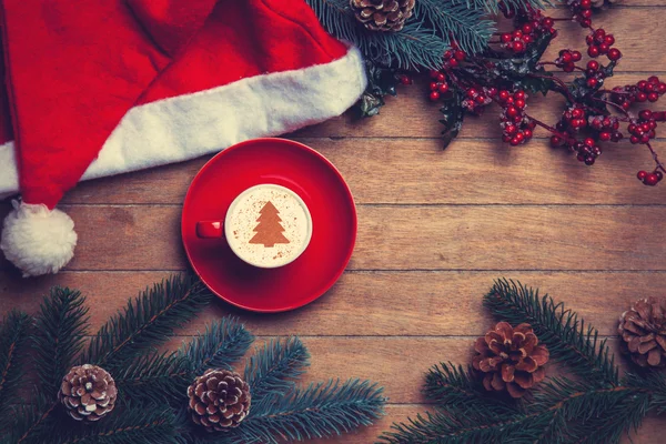 Cappuccino con sombrero de Navidad y pino sobre mesa de madera . —  Fotos de Stock