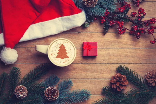 Kopje koffie en geschenk doos met pijnbomen en hoed op houten tafel. — Stockfoto