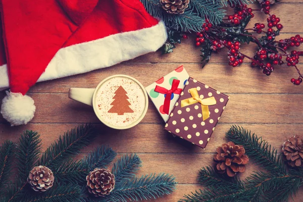 Kopje koffie en geschenk doos met pijnbomen en hoed op houten tafel. — Stockfoto