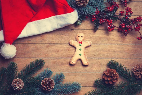 Gingerbread man and christmas hat on wooden table. — Stock Photo, Image