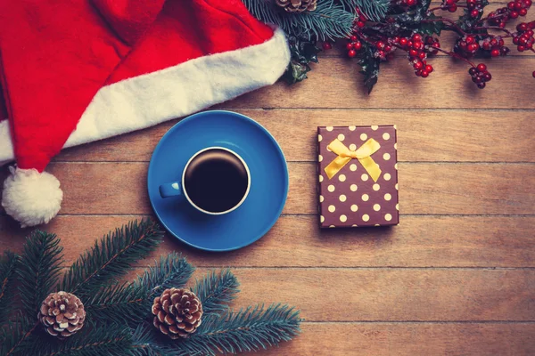 Taza de café y caja de regalo con pino y sombrero en mesa de madera . —  Fotos de Stock