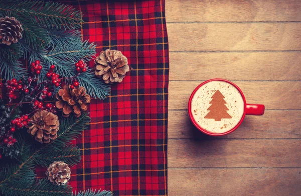 Cappuccino and  pine branch with tartan on wooden table. — Stock Photo, Image