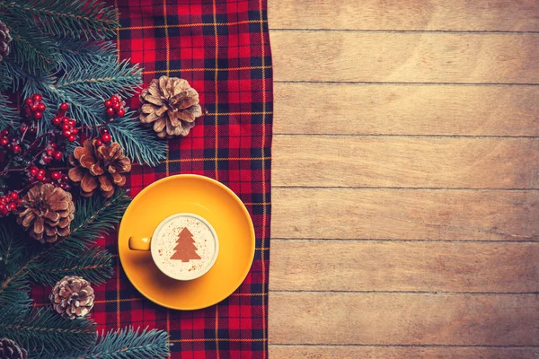 Cappuccino och pine gren med tartan på träbord. — Stockfoto