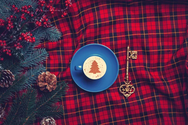 Cappuccino and pine branch  with key on tartan background — Stock Photo, Image